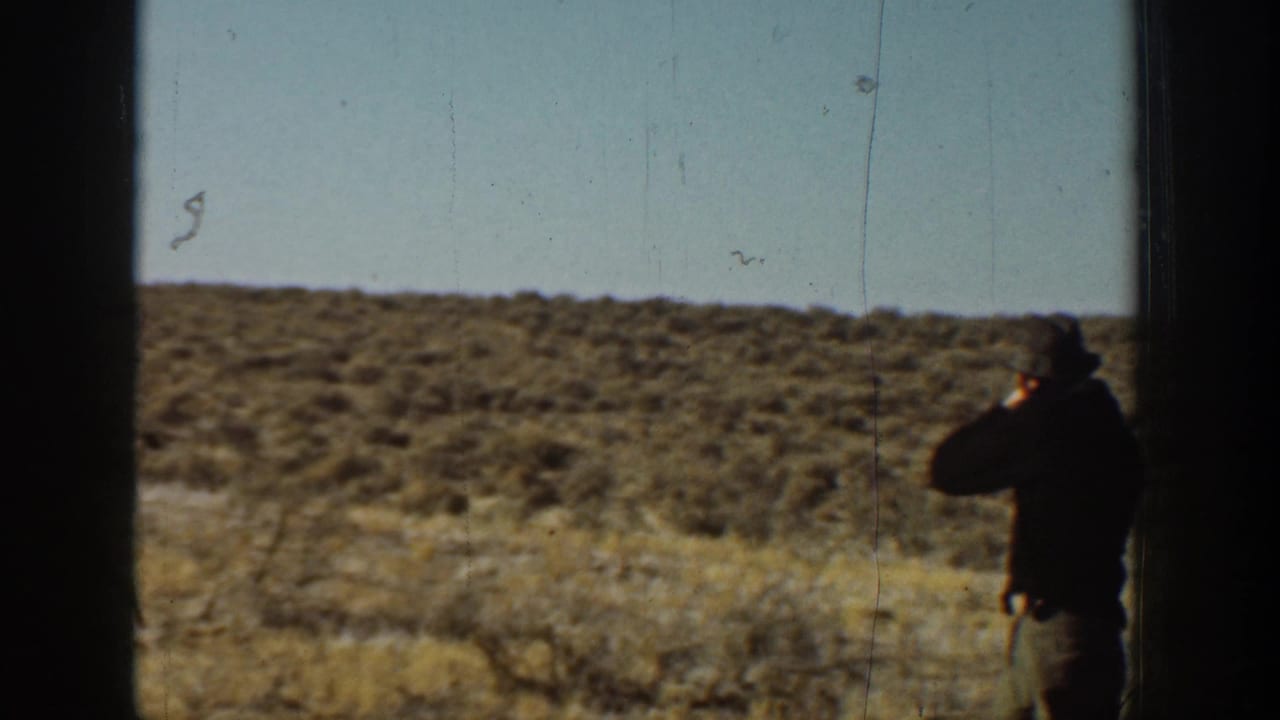 1936 California home-movie frame with the man near the right edge, hand raised as if whistling against dry hillside and sky.