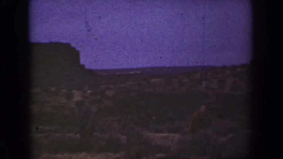 1930s California 8mm frame with purple-tinted sky, a low dark horizon, and rough semi-desert foreground.