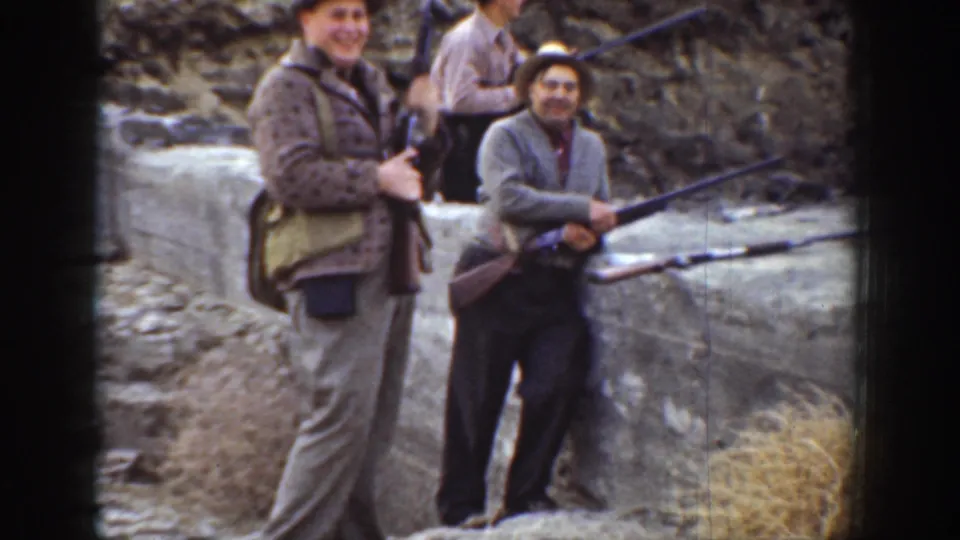 1936 California home-movie frame showing two men with rifles looking toward the camera at an outdoor shooting range.