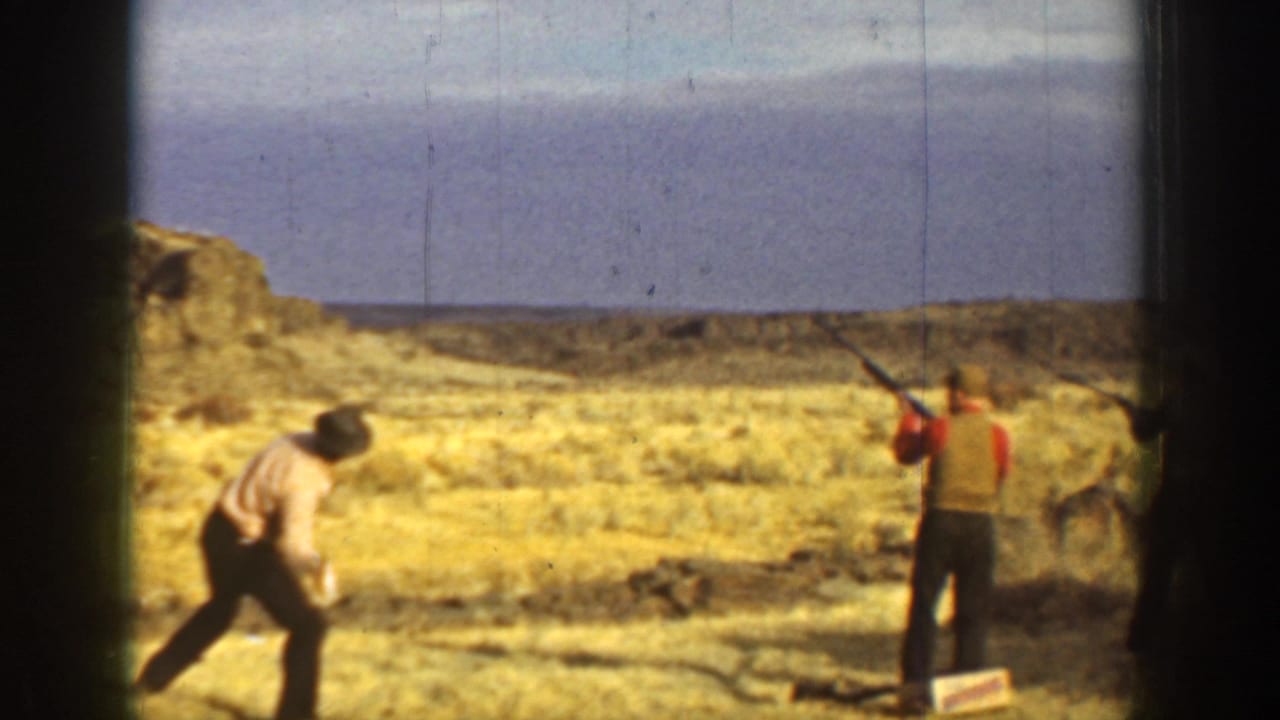 A man prepares near the ground while another aims a shotgun across an open California landscape in the supplied 1936 clip.