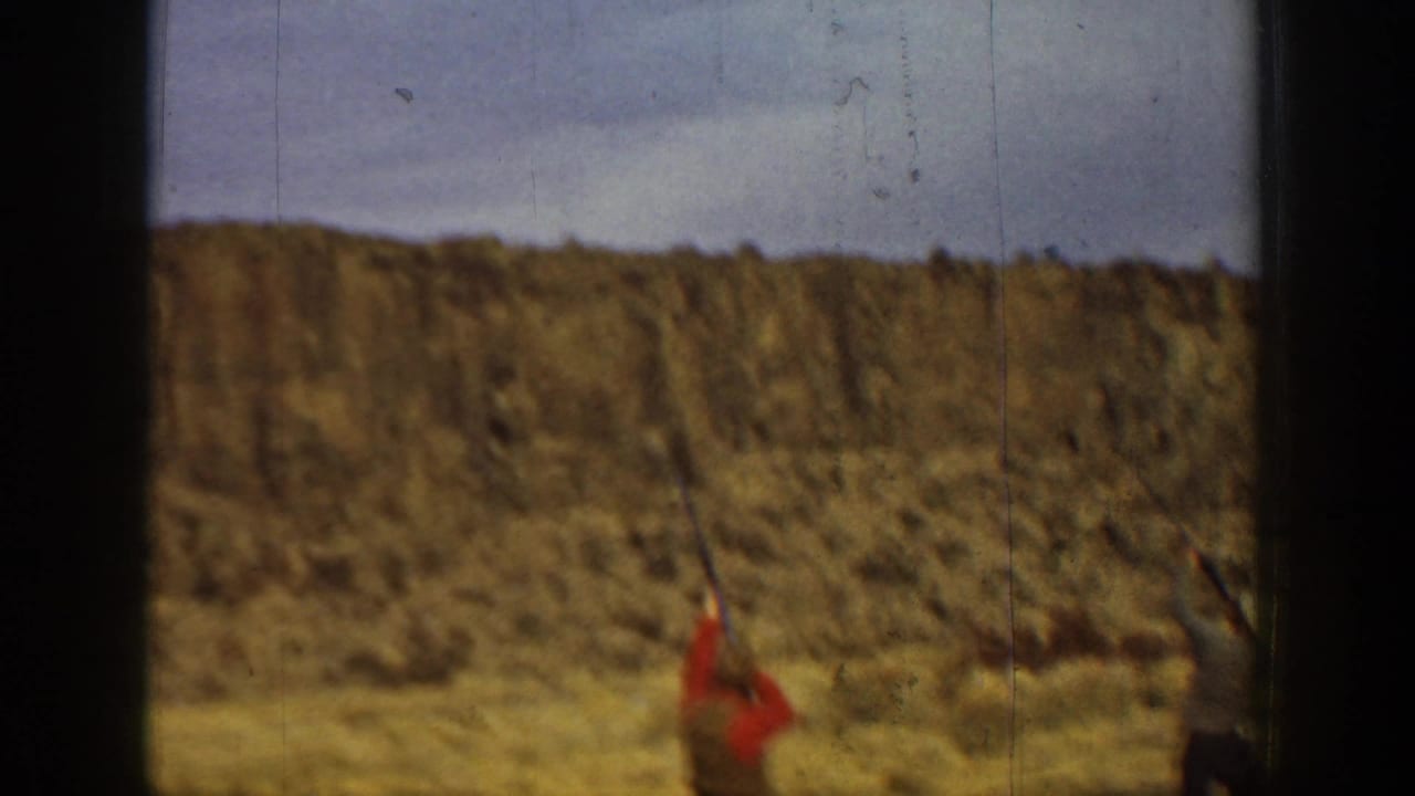 1936 California 8mm frame showing a blurred man in red in a dry open field with low hills and dark gate edges.