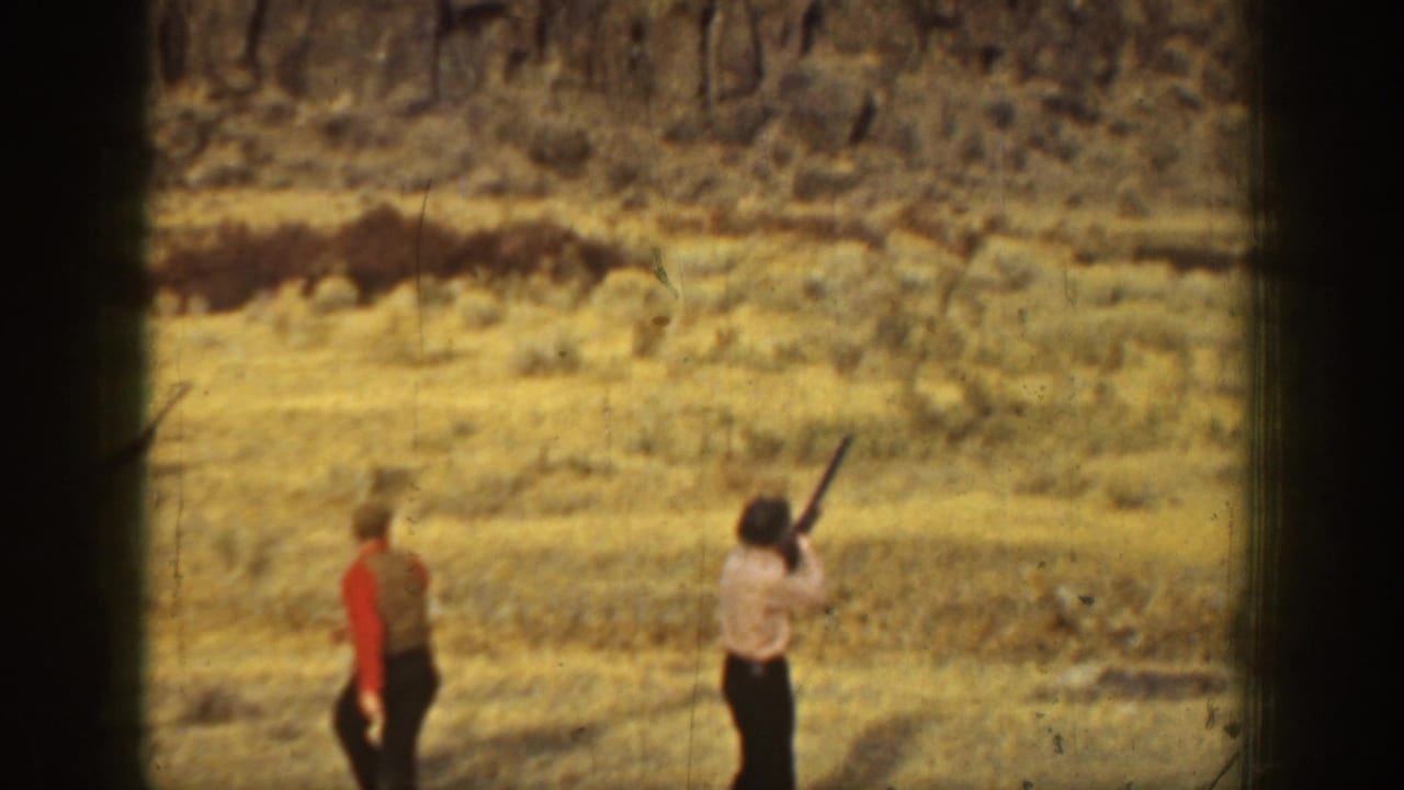 1936 California home-movie frame with a man aiming upward during target practice in an arid landscape.
