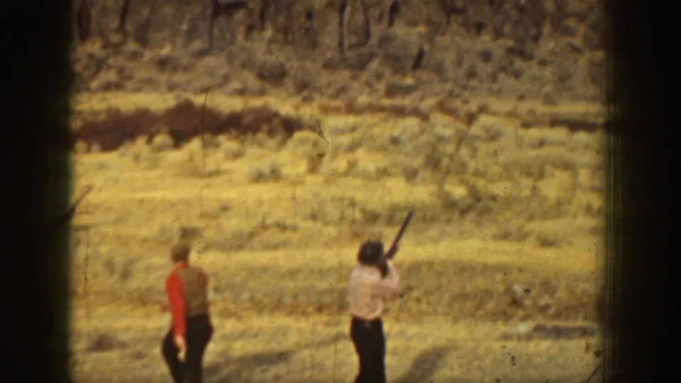 1936 California home-movie frame with a man aiming upward during target practice in an arid landscape.