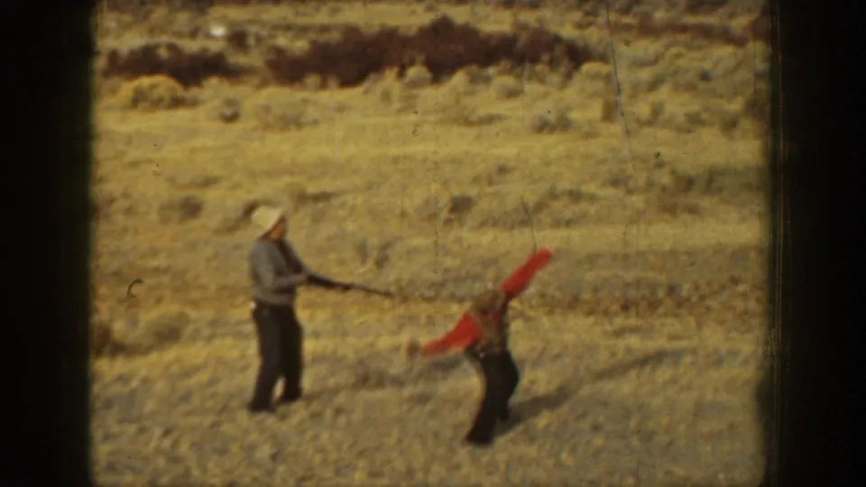 1936 California 8mm frame showing a target-shooting moment with one man holding a shotgun and another assisting.