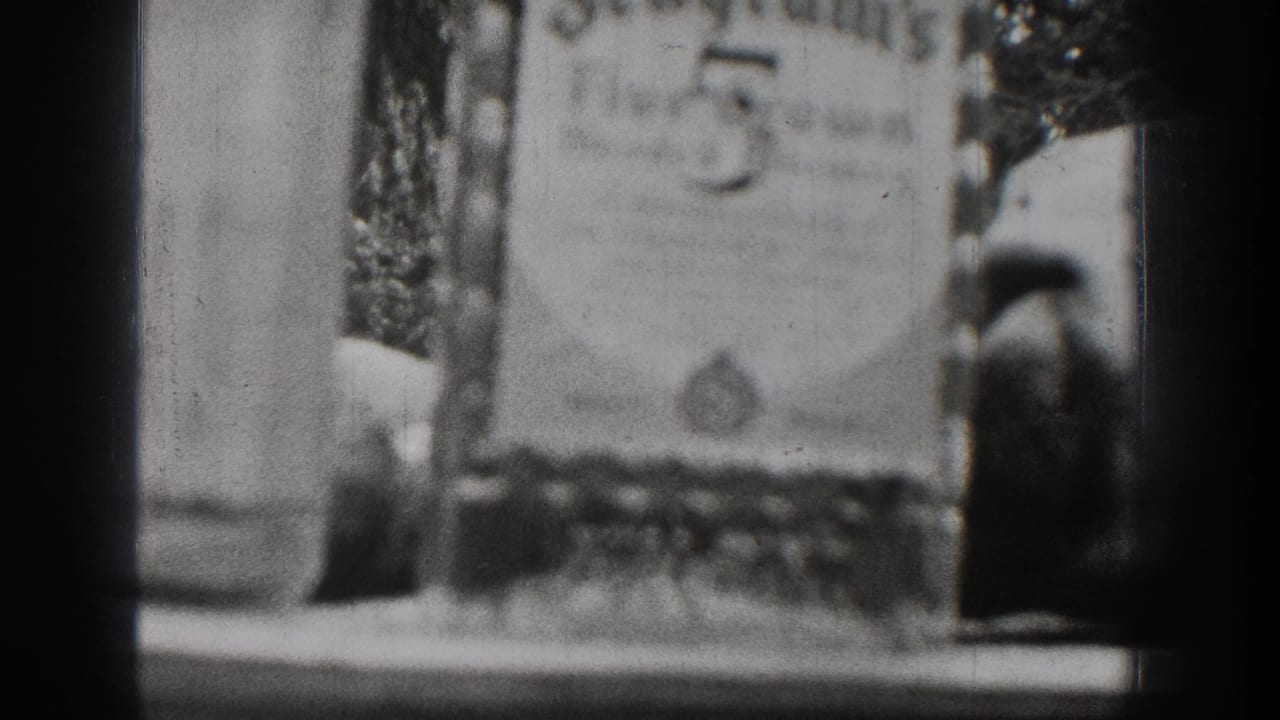 Soft black-and-white close-up with a blurred sign or label near a tabletop and dark film borders.