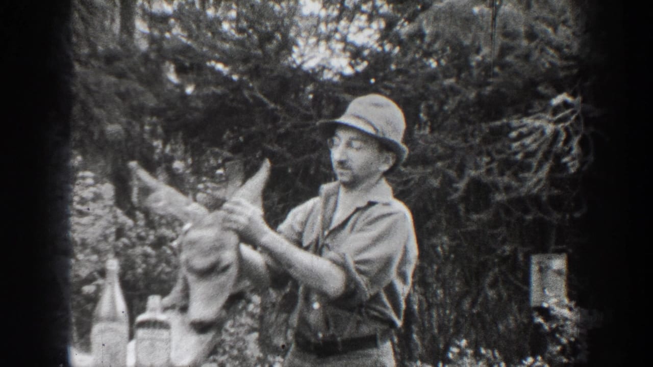 In 1939 Chelan, Washington footage, a man in a hat and work shirt handles a deer head with antlers in a wooded setting.