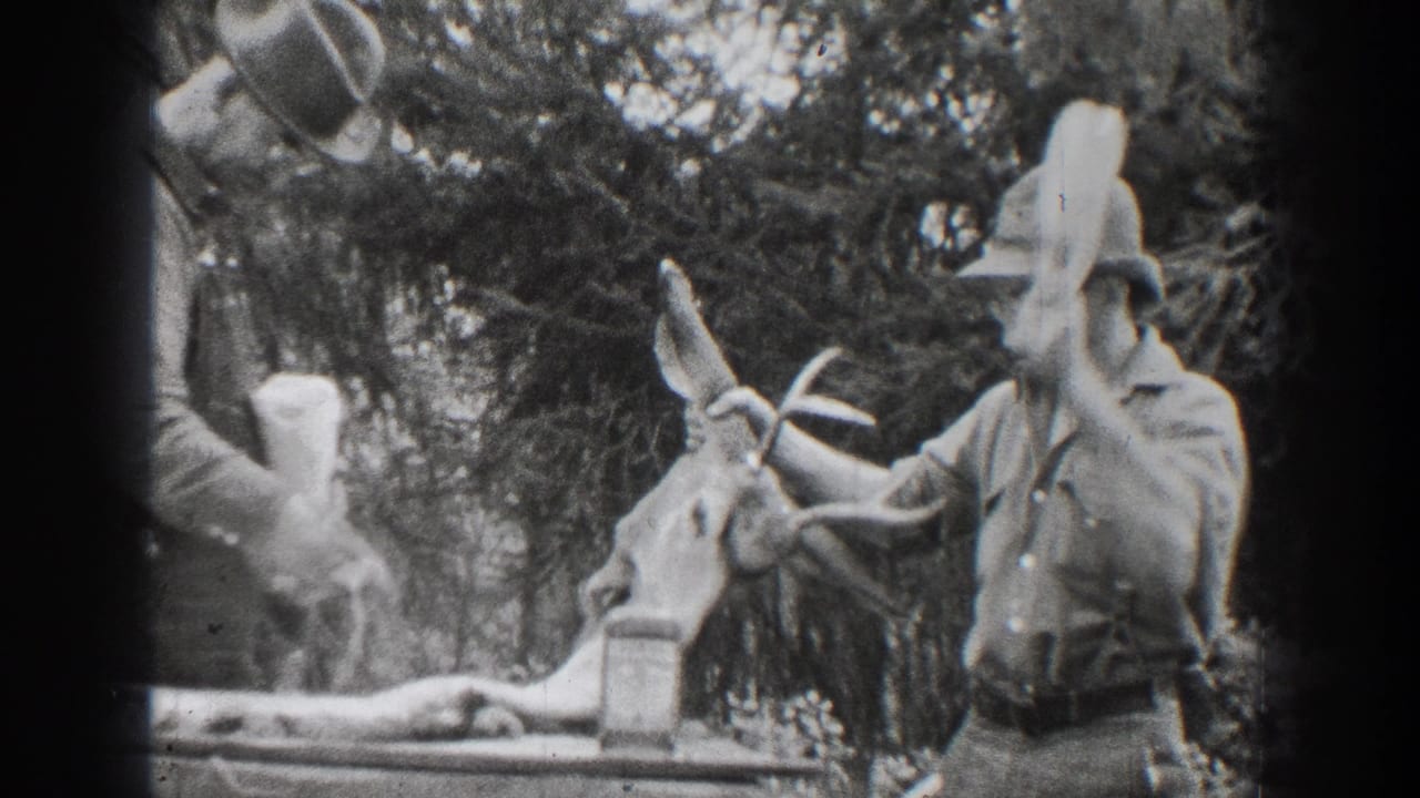 1939 Chelan-area home-movie frame showing men in hats near a deer in a wooded outdoor setting.