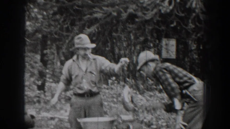 In 1939 Chelan, Washington home-movie footage, two adult men appear to handle equipment near a metal basin among trees.