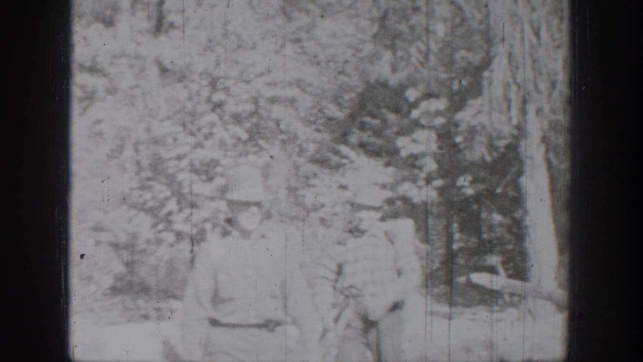 Two people appear seated near a tree in the outdoor Chelan, Washington home-movie scene, with details softened by exposure and grain.