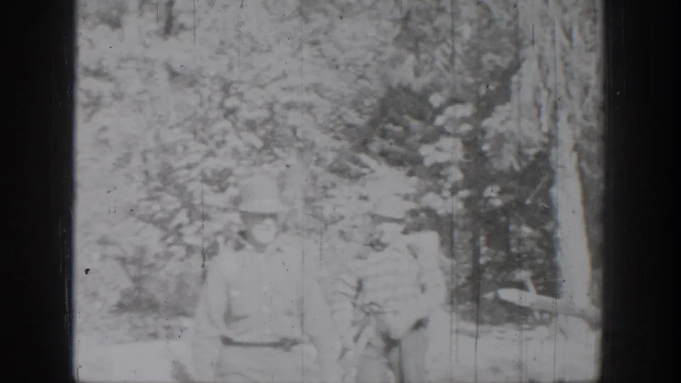 Two people appear seated near a tree in the outdoor Chelan, Washington home-movie scene, with details softened by exposure and grain.