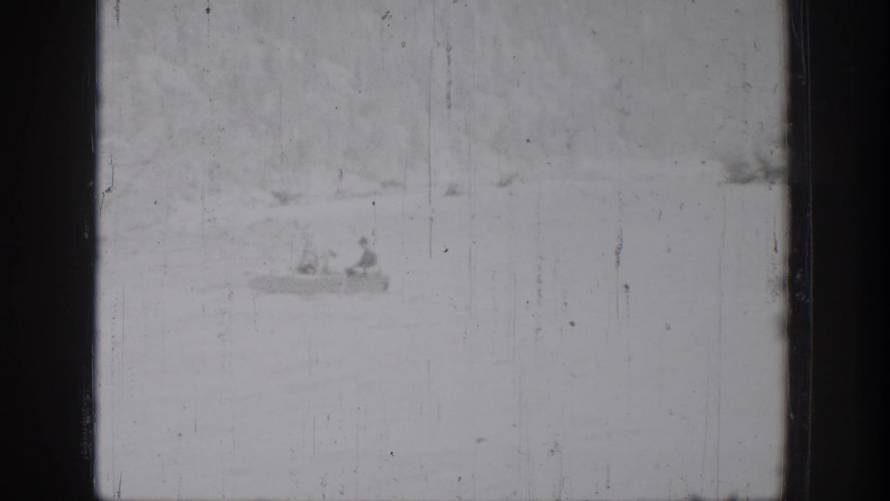 Chelan 1939 home-movie frame with a small boat carrying two distant figures on a bright lake surface.