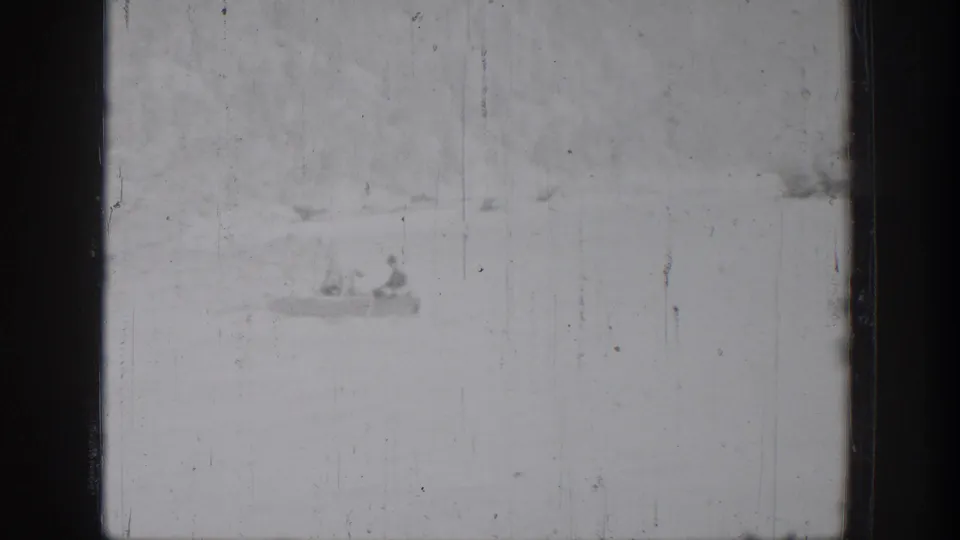 Chelan 1939 home-movie frame with a small boat carrying two distant figures on a bright lake surface.