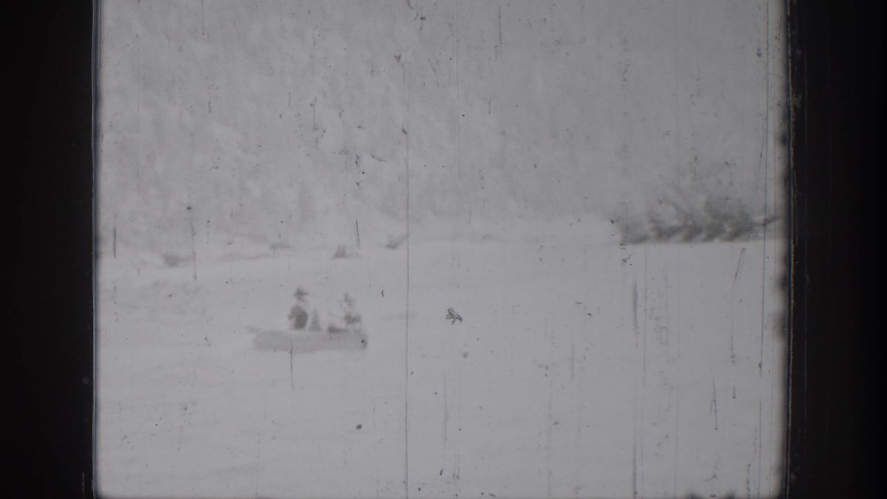 A distant canoe carrying two people crosses the lake at Chelan, Washington, in grainy 1939 8mm footage.