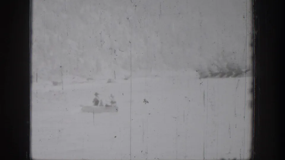 A distant canoe carrying two people crosses the lake at Chelan, Washington, in grainy 1939 8mm footage.