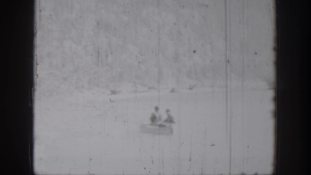 Two men appear in a distant rowboat on Chelan lake water in 1939 black-and-white 8mm footage, with soft focus and scratches.
