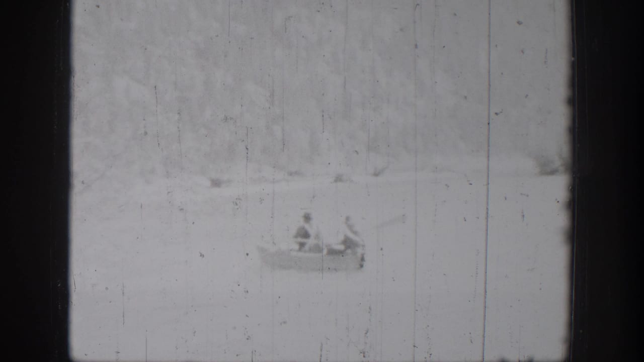 The rowboat remains distant on the lake in this 1939 Chelan home-movie frame, with two occupants faintly visible.