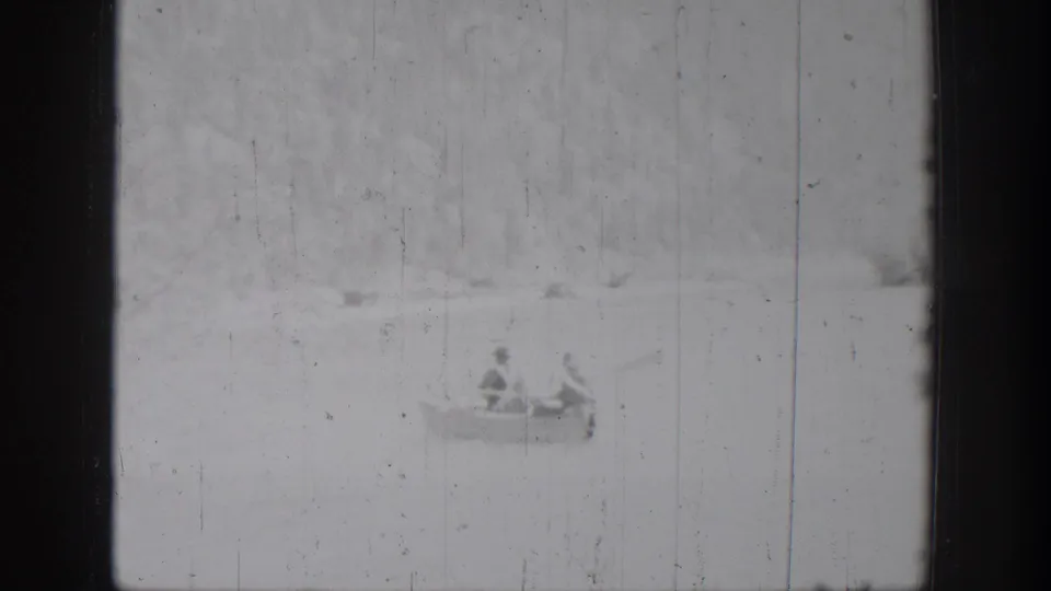The rowboat remains distant on the lake in this 1939 Chelan home-movie frame, with two occupants faintly visible.