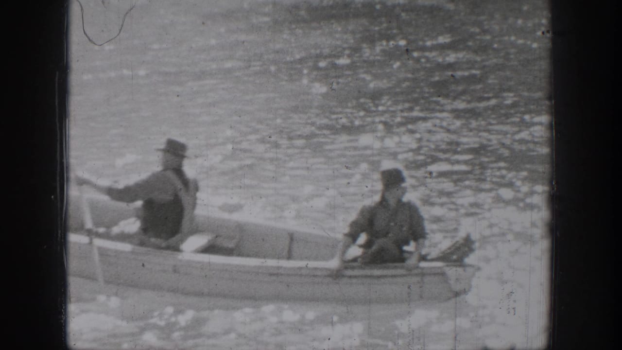 In Chelan, Washington, two men in period hats sit in a small rowboat on calm water in 1939 home-movie footage.
