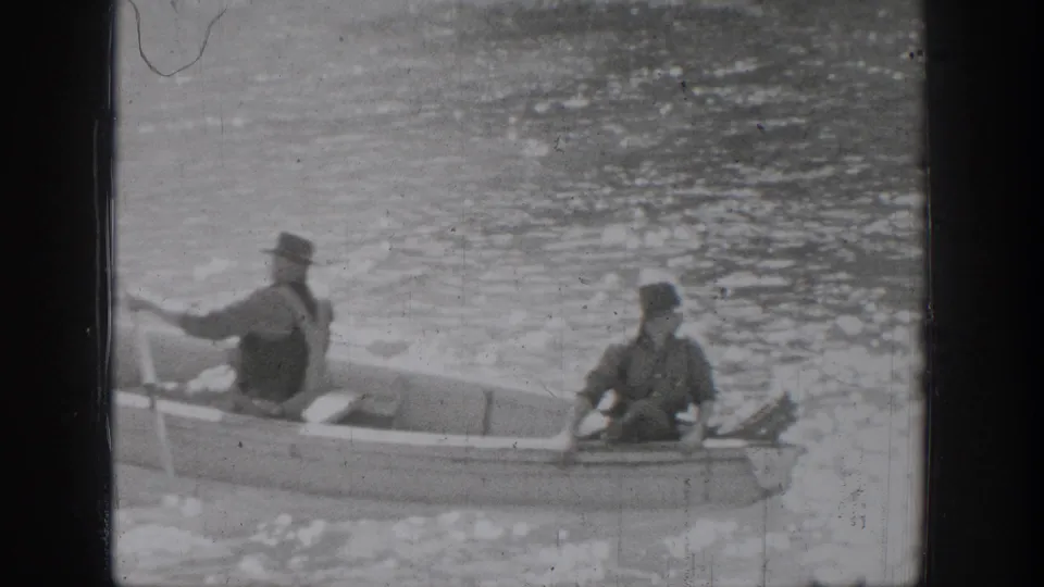 In Chelan, Washington, two men in period hats sit in a small rowboat on calm water in 1939 home-movie footage.