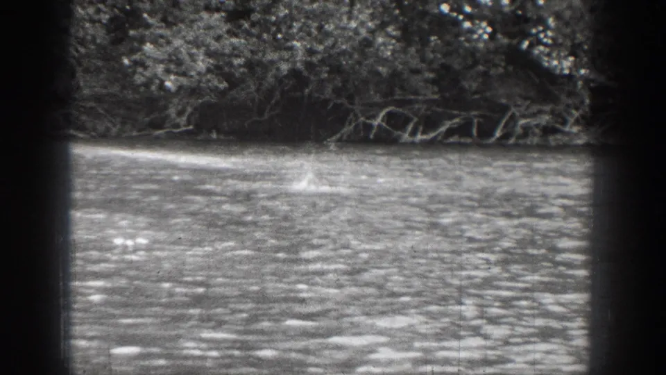 The closing 1939 Chelan frame lingers on rippled water and a wooded shoreline after the boat has moved out of view.