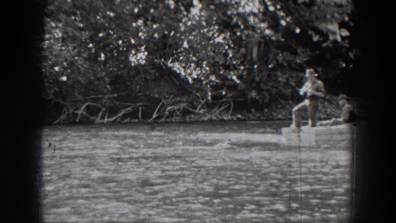 Chelan home-movie frame with a fisherman standing in a rowboat as the boat moves toward the edge of the frame.