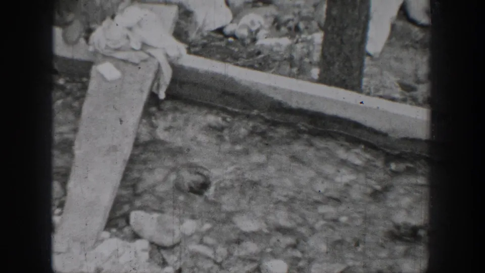 Chelan riverbank frame from 1939 8mm footage, with a slanted board, cloth, rocks, and flowing water visible.