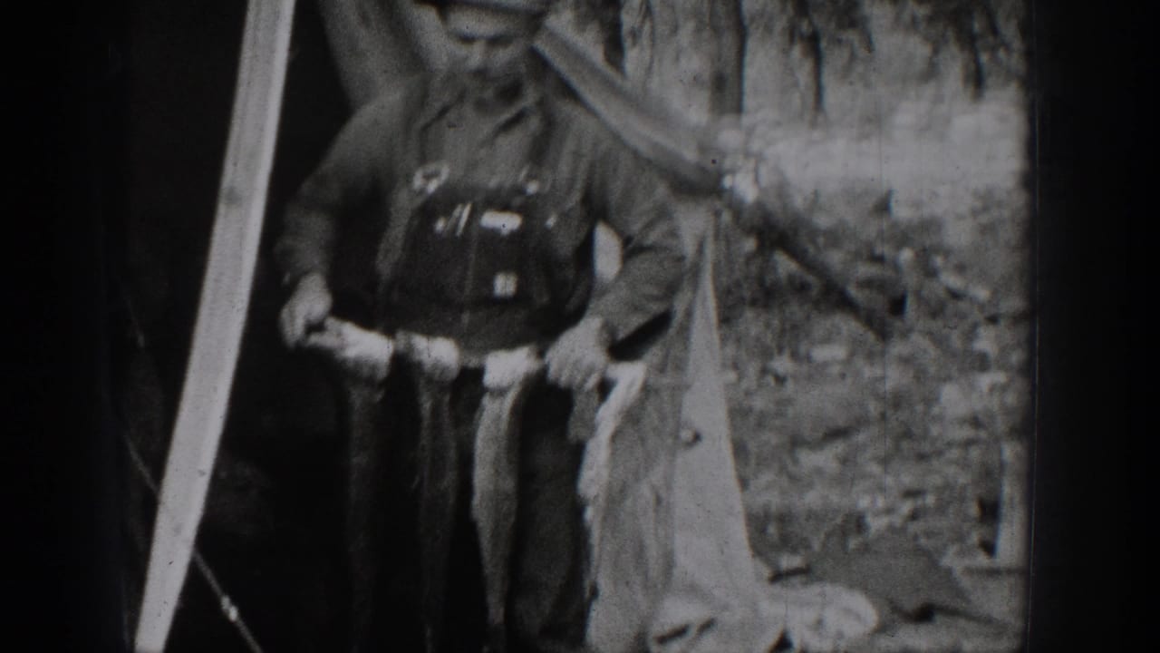 1939 Chelan, Washington home-movie frame showing an older man and a boy posing in a forested setting with a fish catch.