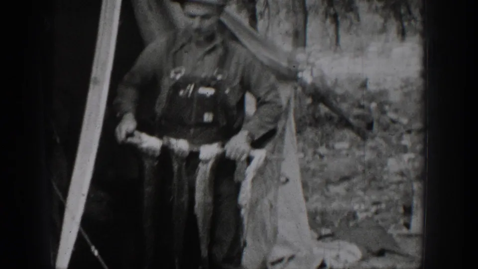 1939 Chelan, Washington home-movie frame showing an older man and a boy posing in a forested setting with a fish catch.