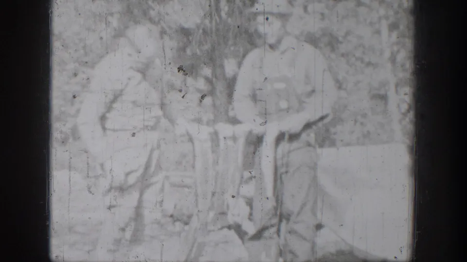 Overexposed 8mm frame from the Chelan fishing scene, with two figures faintly visible beside the displayed catch.