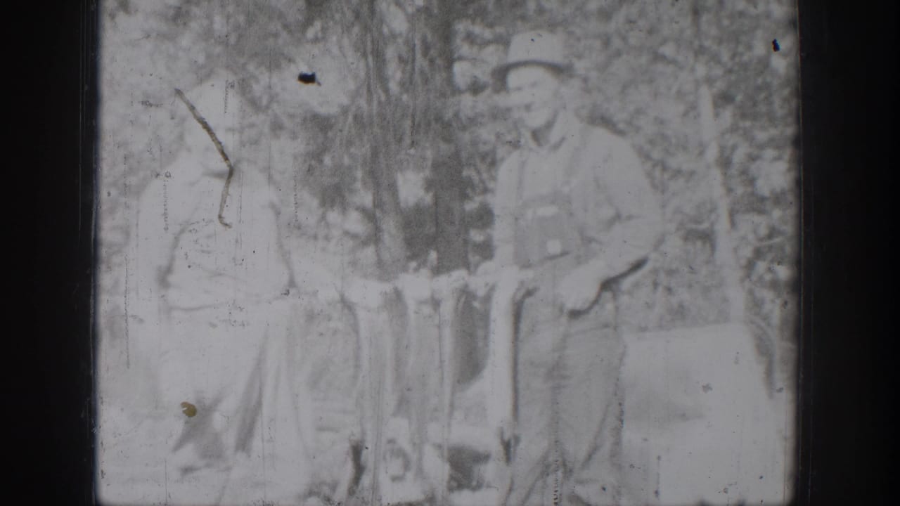 Chelan, Washington 8mm frame showing an older man in overalls and a boy beside a string of fish in a wooded area.