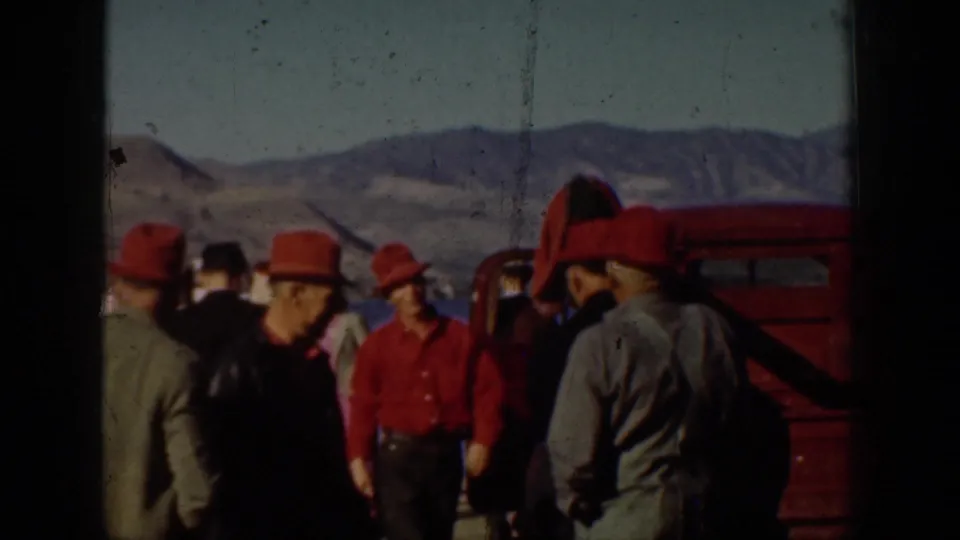 1939 Chelan, Washington home-movie frame showing men in red hats and period outdoor clothing gathered beside a lake dock.