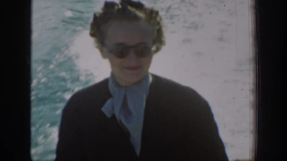 1939 Chelan, Washington frame of a woman in sunglasses looking downward during a sunny boat ride on the lake.