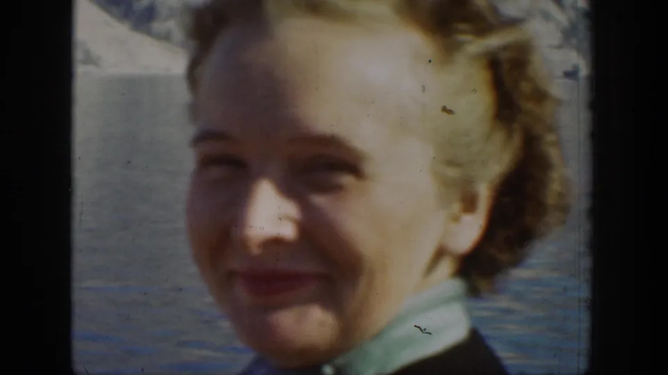 A smiling woman appears beside lake water in 1939 Chelan, Washington home-movie footage.