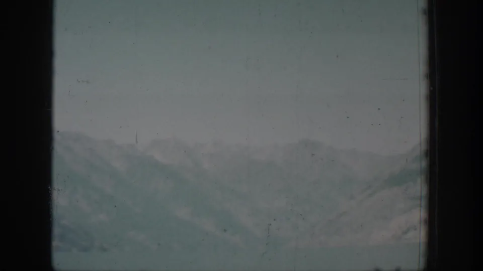 Chelan-area mountain ridges appear through a dark window frame in faded 1939 8mm travel footage.