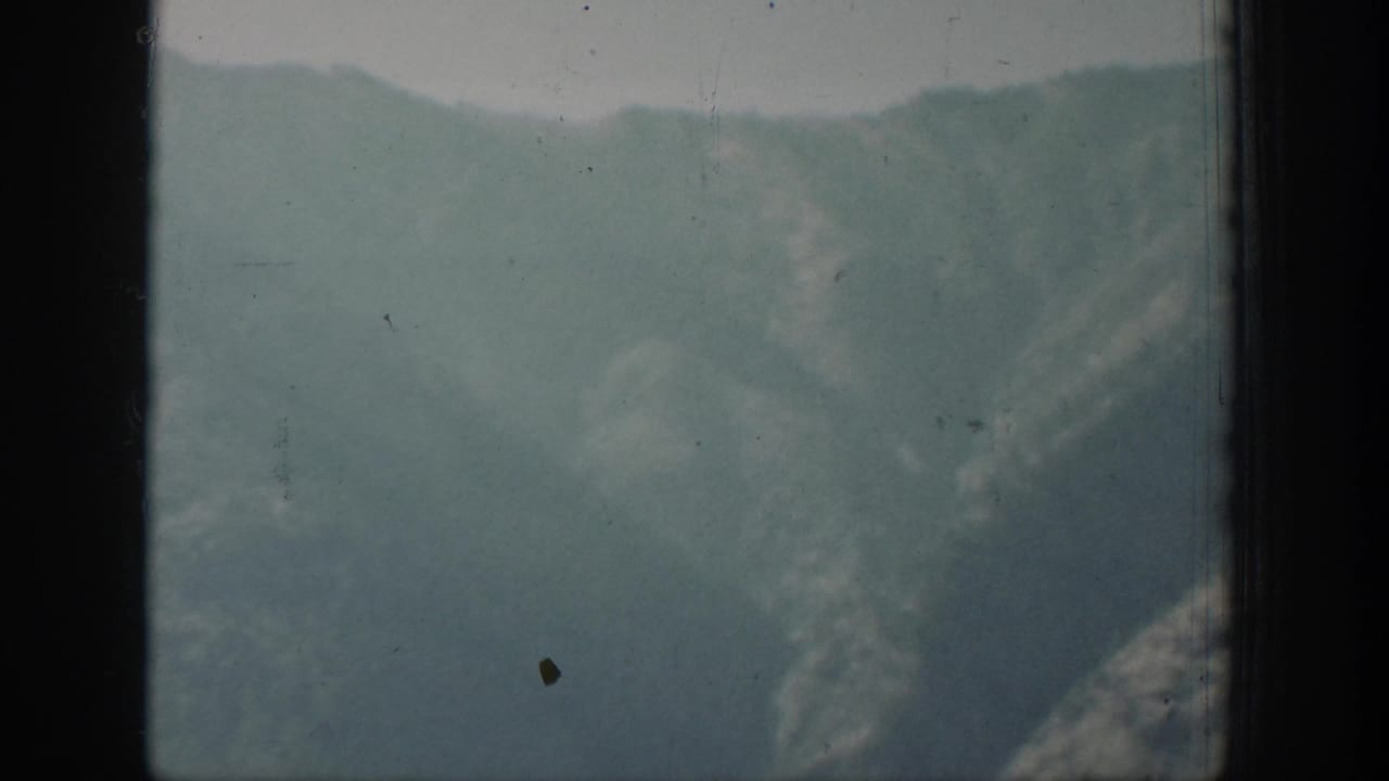 Faded 8mm view of blue-green lake or river water below mountain slopes near Chelan, Washington.