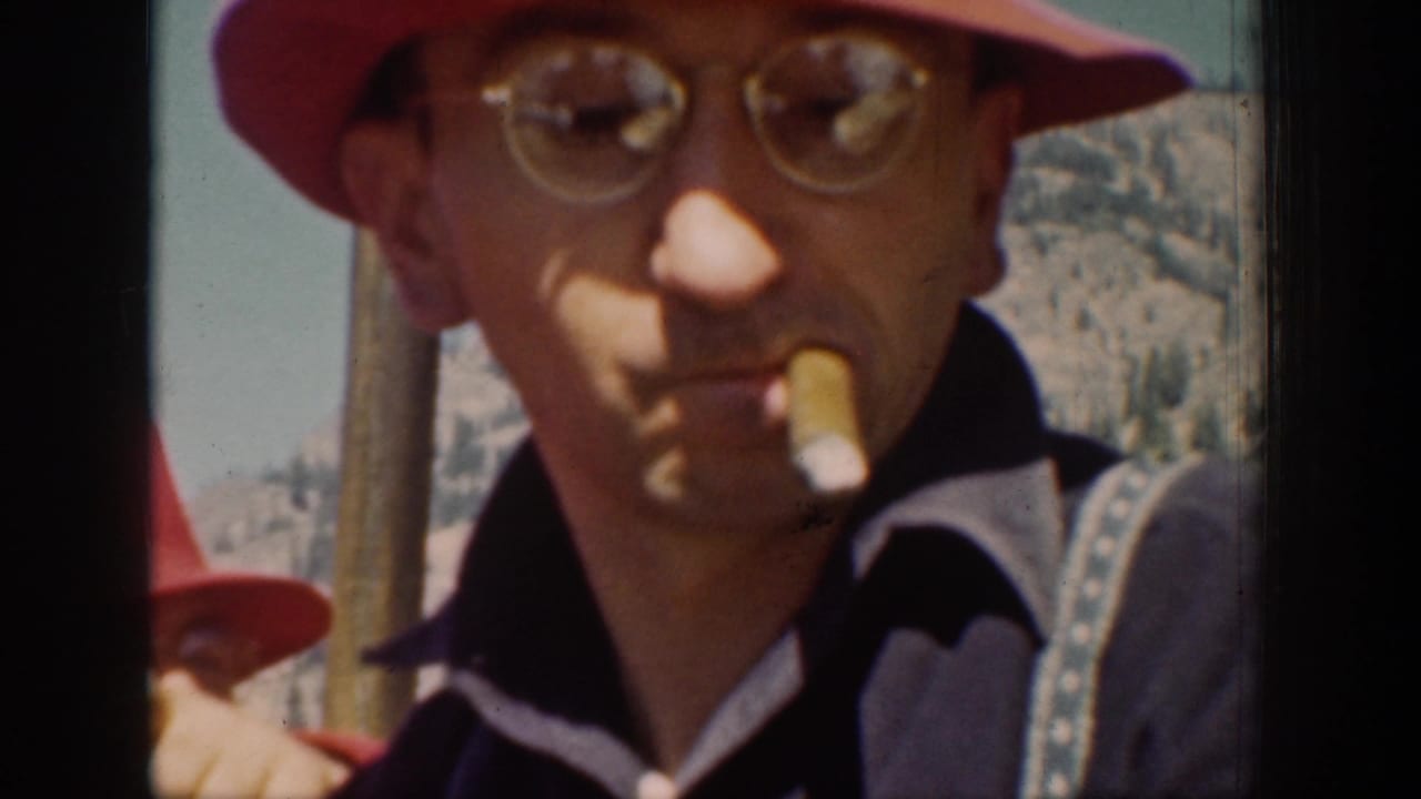 An adult traveler in a red hat and round glasses faces the camera with a cigarette during a 1939 Chelan mountain outing.