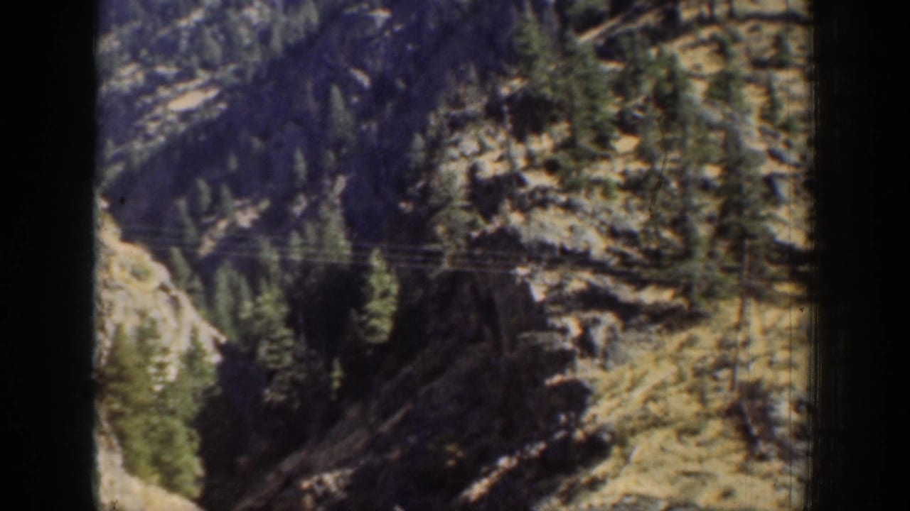 1939 Chelan-area 8mm frame showing rocky evergreen slopes through a dark vertical window or film-frame border.