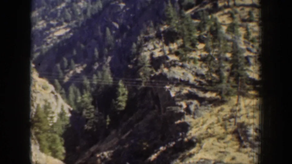 1939 Chelan-area 8mm frame showing rocky evergreen slopes through a dark vertical window or film-frame border.