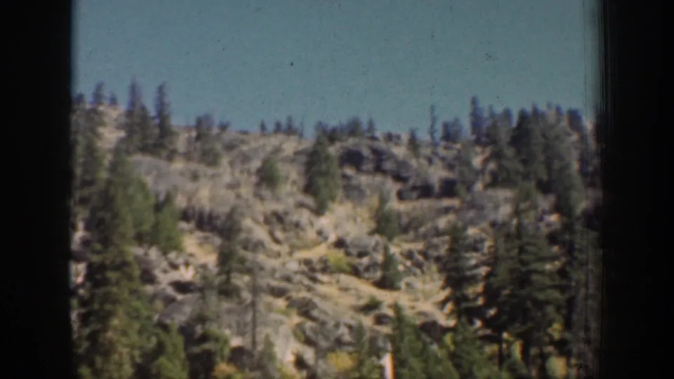 Chelan, Washington mountain scenery with scattered evergreens, exposed rock, blue sky, and dark 8mm frame borders.