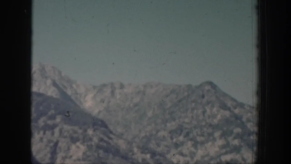 1939 Chelan, Washington home-movie frame showing distant mountain ridges through dark framing with soft focus and faded color.