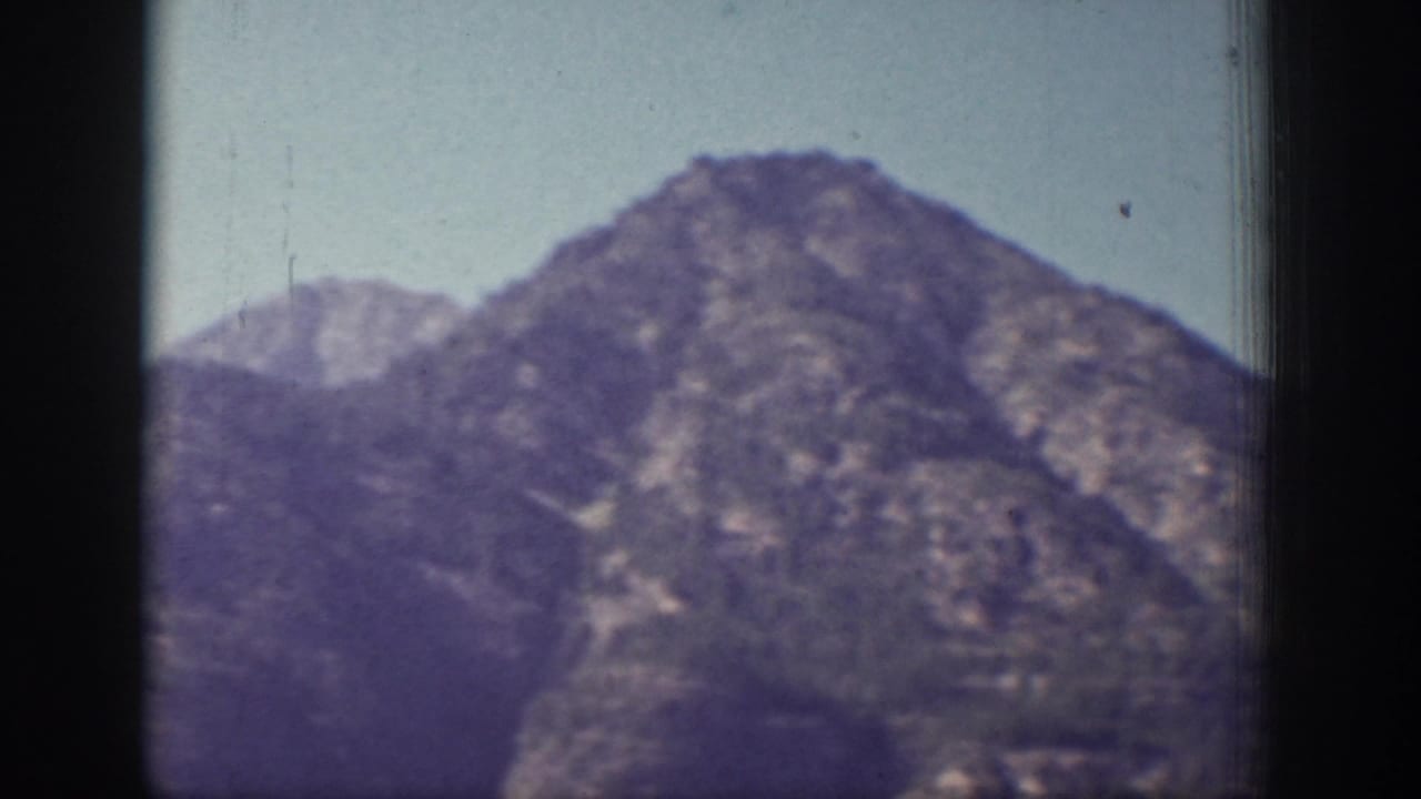 Mountain peak and ridgeline seen through a soft, grainy 8mm frame.