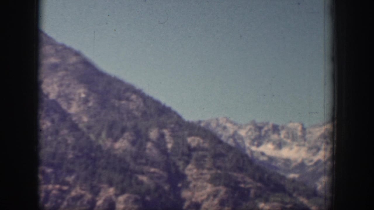 1939 Chelan, Washington home-movie frame showing a wider mountain valley with ridges and small snow patches.