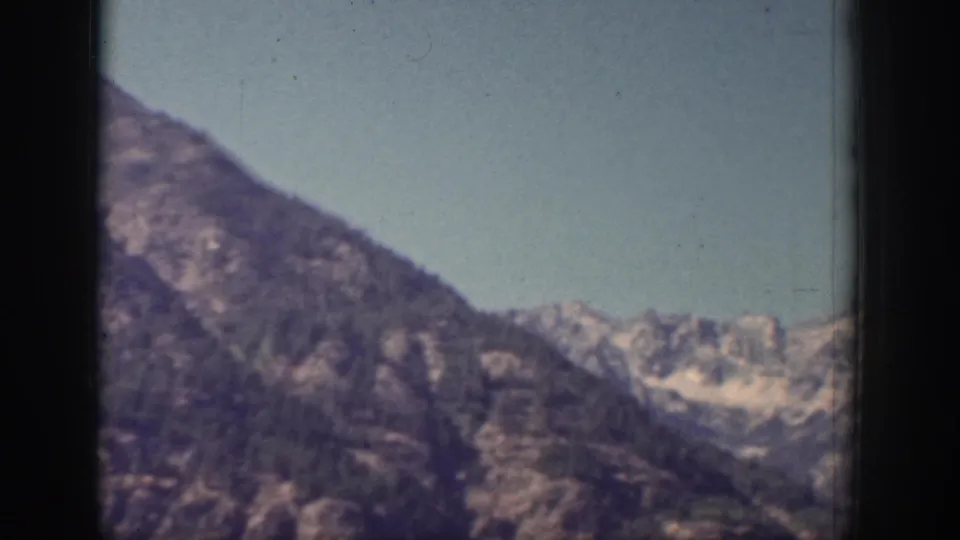 1939 Chelan, Washington home-movie frame showing a wider mountain valley with ridges and small snow patches.