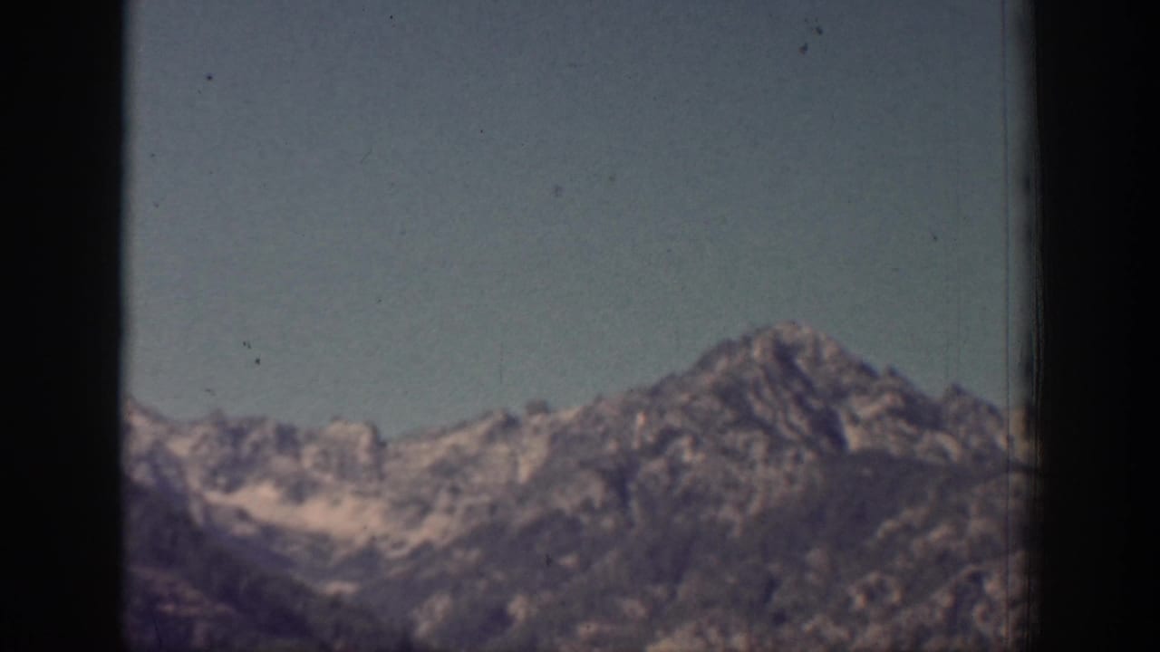 1939 Chelan, Washington frame showing distant ridges and a rocky peak beneath clear sky with visible film texture.