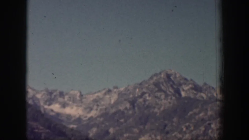 1939 Chelan, Washington frame showing distant ridges and a rocky peak beneath clear sky with visible film texture.