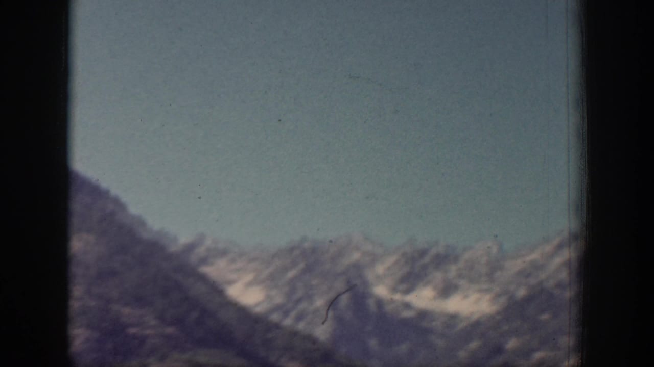 A snow-dusted mountain ridge appears beyond dark window framing in the Chelan, Washington travel footage.