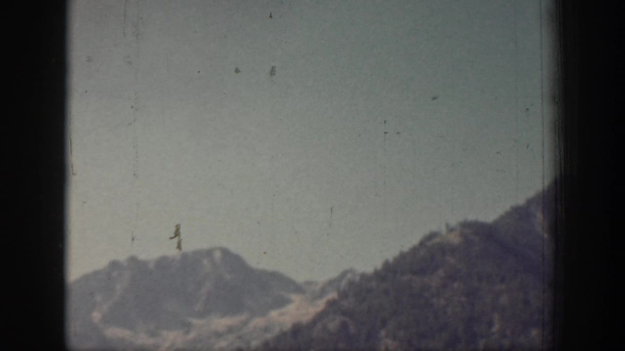 A hazier 1939 Chelan mountain view shows a low ridge and open sky, with dust marks and soft 8mm color visible.