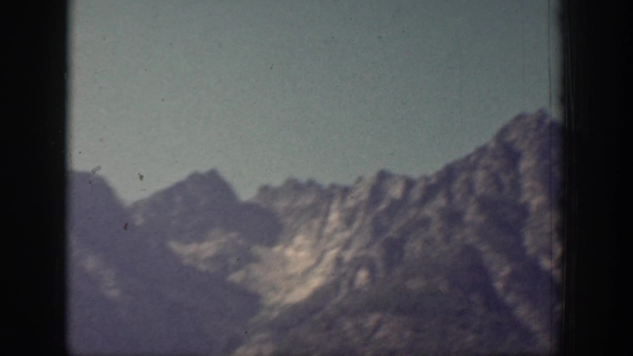 Soft 8mm view of layered Chelan-area mountain ridges with pale sky and visible gate edge.