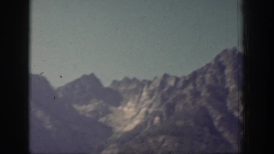 Soft 8mm view of layered Chelan-area mountain ridges with pale sky and visible gate edge.