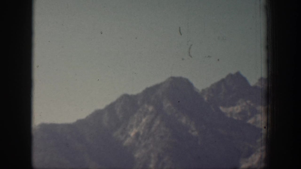 Faded 1939 Chelan 8mm frame with a soft mountain silhouette, ridgelines, and visible film specks.